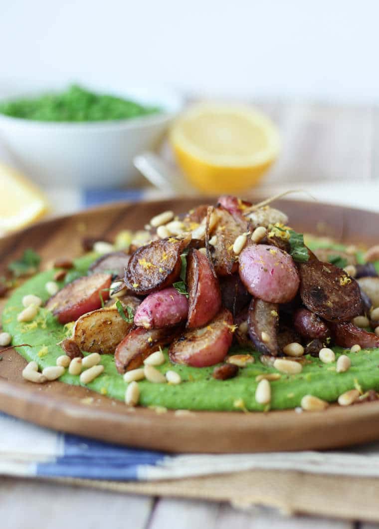 A close up of a plate of za\'atar roasted radishes over top of a pea puree.