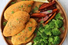 An overhead photo of a brown plate with shake and bake chicken breasts with broccoli florets and vegetable fries.