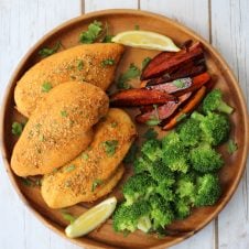 An overhead photo of a brown plate with shake and bake chicken breasts with broccoli florets and vegetable fries.