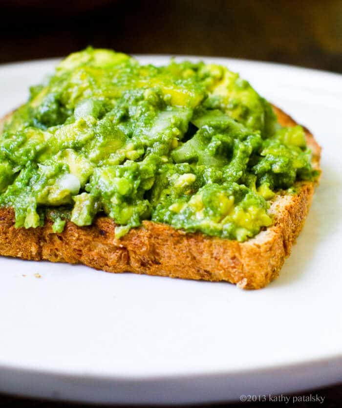 A close up of mashed avocado on toast.