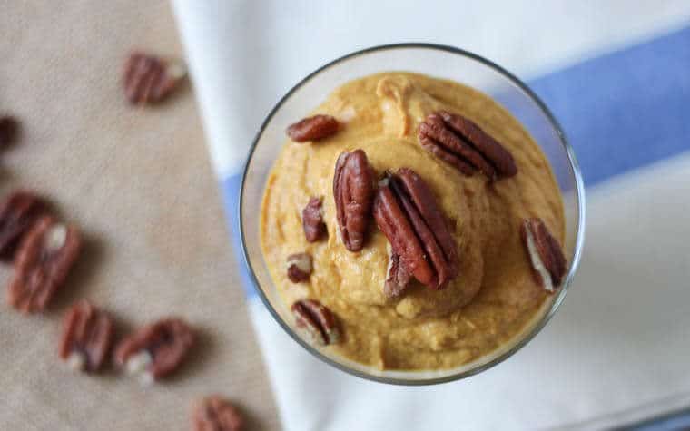 An overhead photo of a glass of pumpkin parfait topped with pecans.