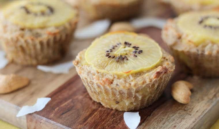 A close up of an oatmeal muffin with a sliced kiwi over top.