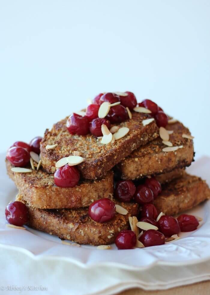 Almond vegan french toast with sour cherries and almonds on a white dish. 