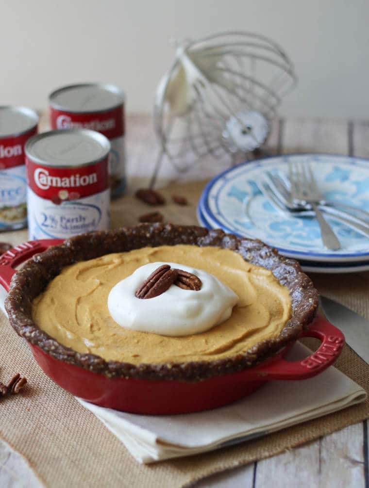 A gluten free pumpkin pie in a red baking dish on a set table.