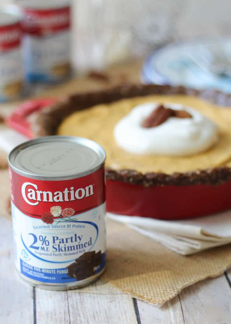 A close up of a can of Carnation in front of a pumpkin pie.