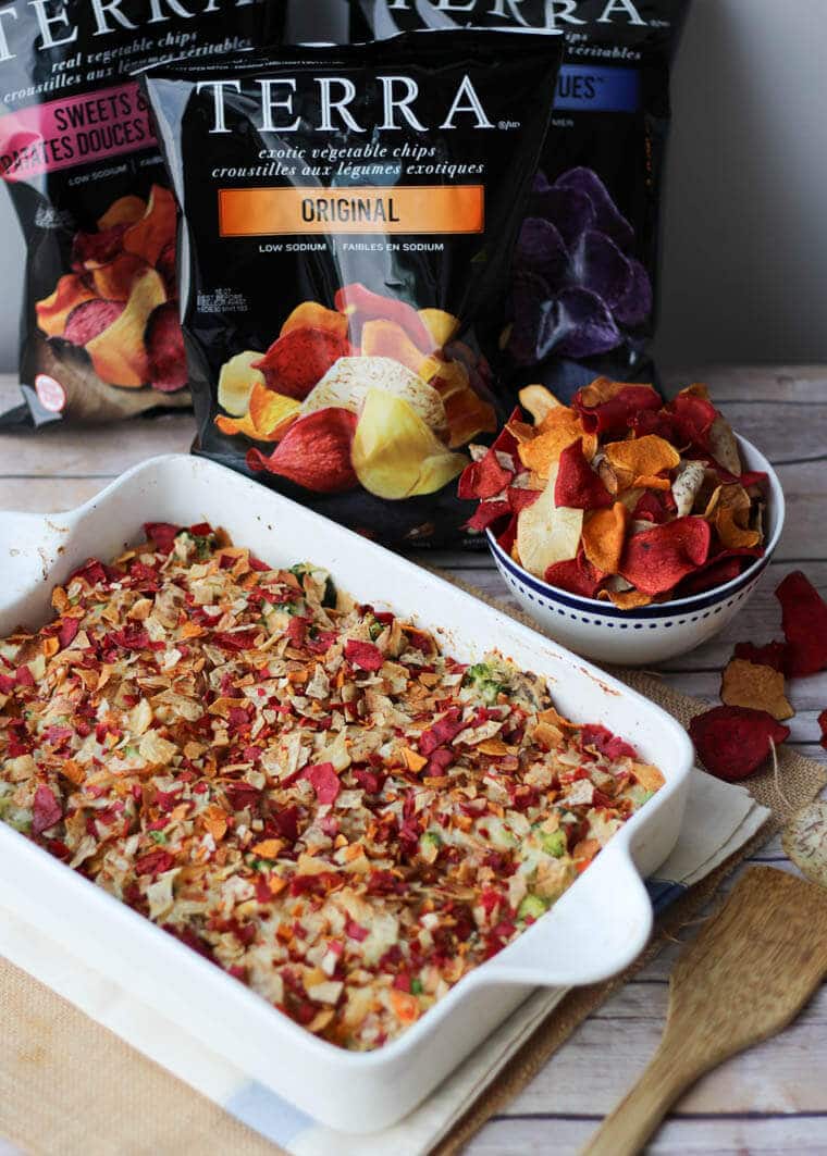 A white casserole dish with a bowl of vegetable chips beside it.