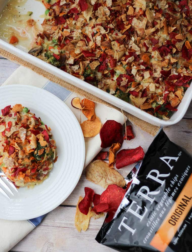 A casserole dish containing a tuna casserole with a plate on the side and Terra chips poured out beside it.