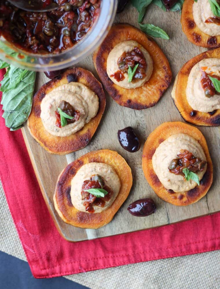 An overhead photo of multiple sundried tomato sweet potato bites on a wooden board.