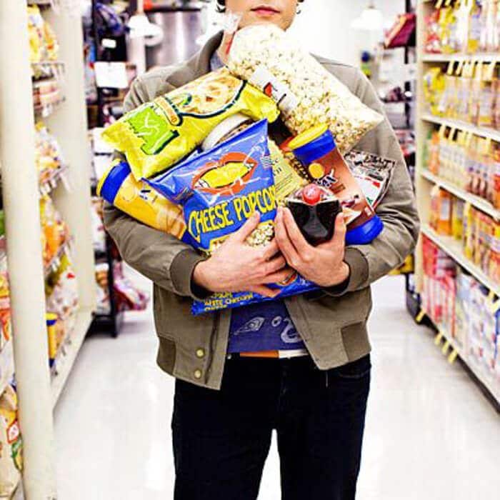 A man standing holding a lot of snacks in his arms.\"