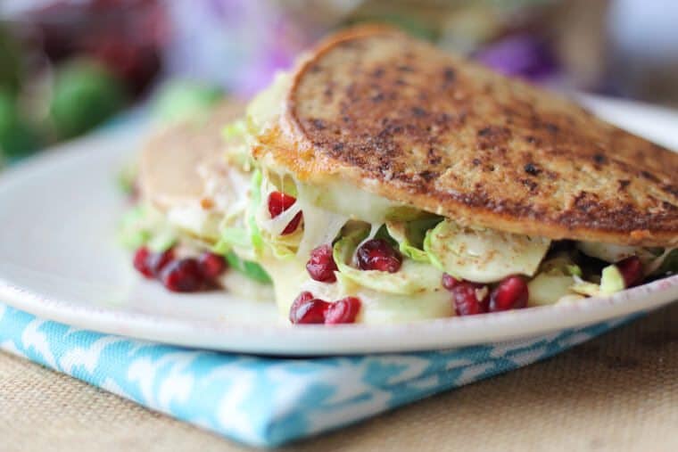 sandwich made with flatbread, cheese, and brussel sprouts on a white plate 