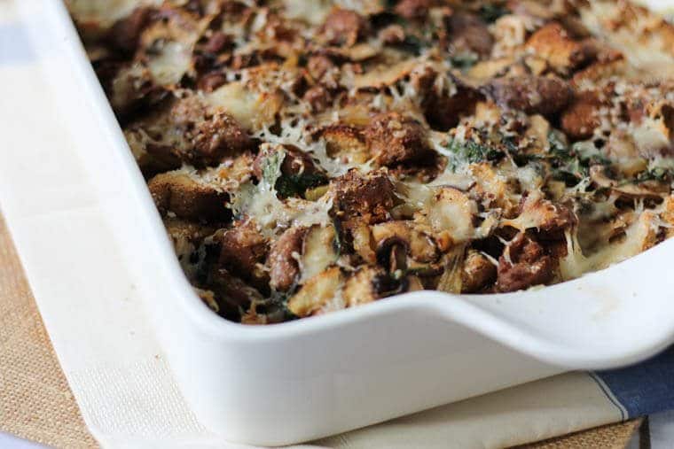 A close up of a corner of a white baking dish with sausage strata.
