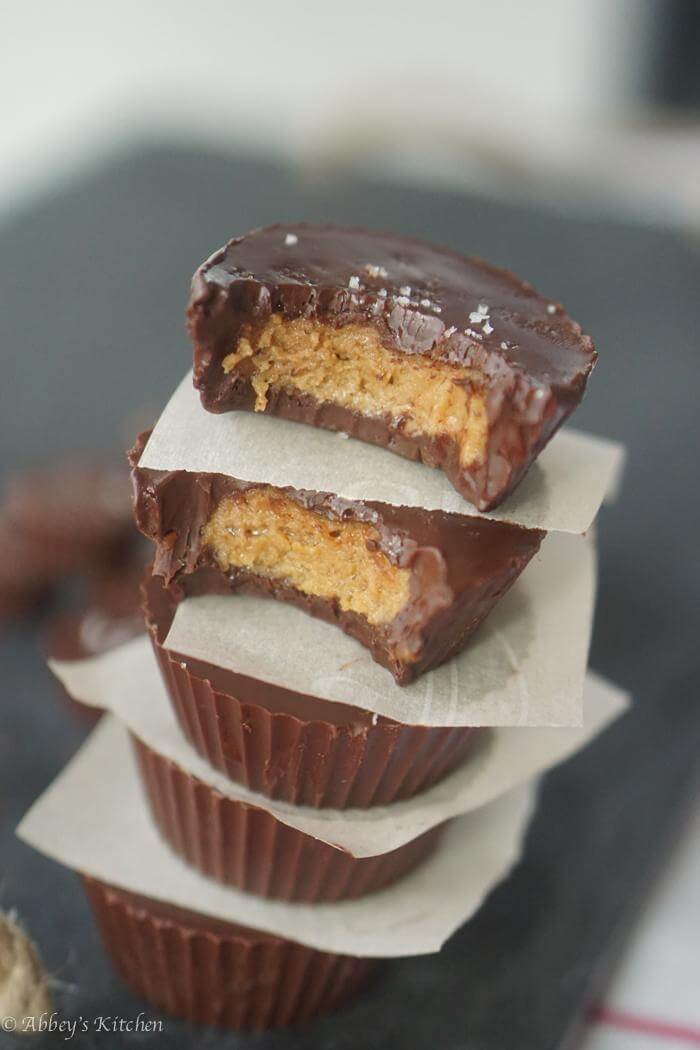 A stack of five peanut butter cup with the top two with a bite taken out of them.\"