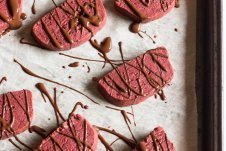 A sheet pan with multiple red velvet shortbread cookies.