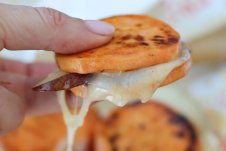 Close up of a hand holding sweet potato grilled cheese sandwich bites.