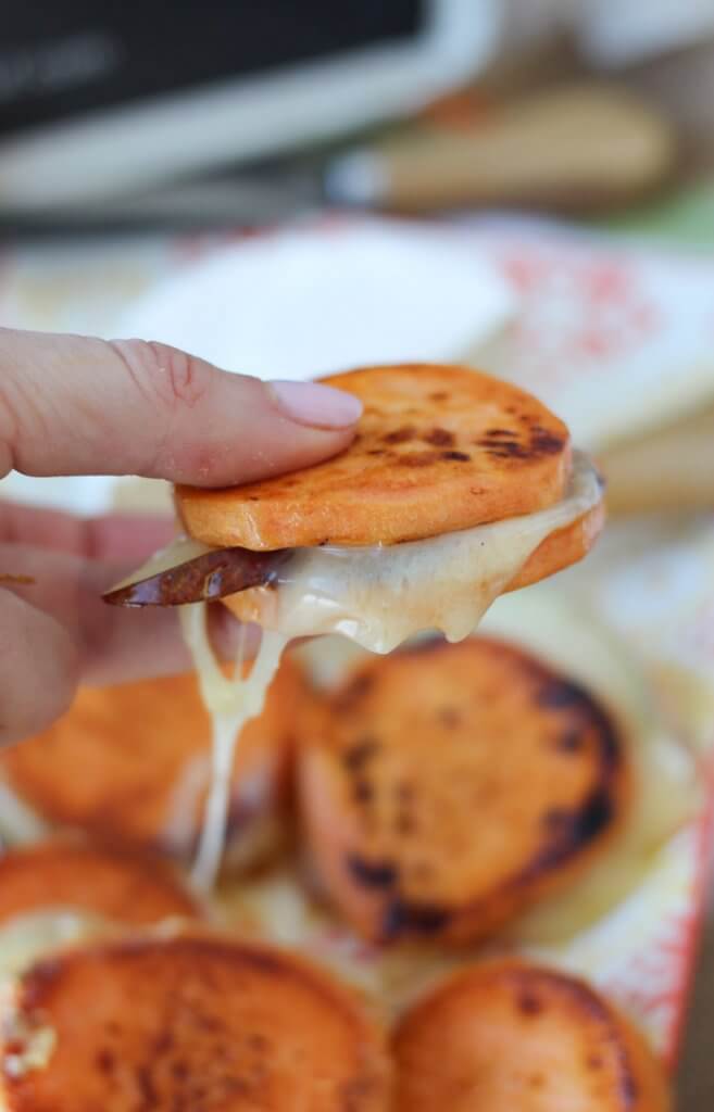 Close up of a hand holding sweet potato grilled cheese sandwich bites.