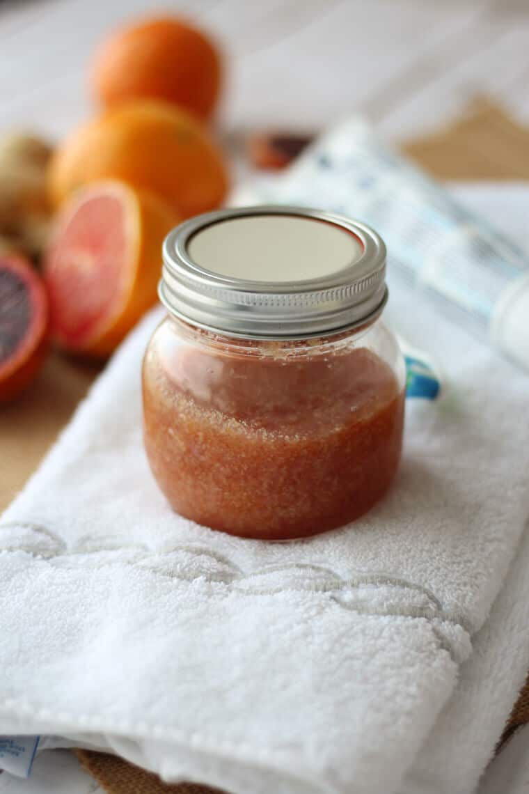 A mason jar with citrus body scrub on a white linen.