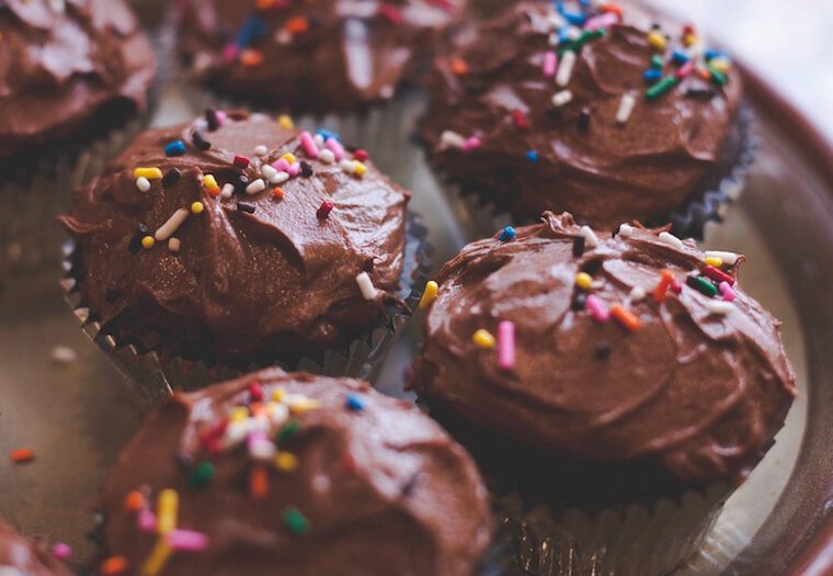close up of Cupcakes with chocolate frosting and sprinkles as a menstrual cycle diet craving