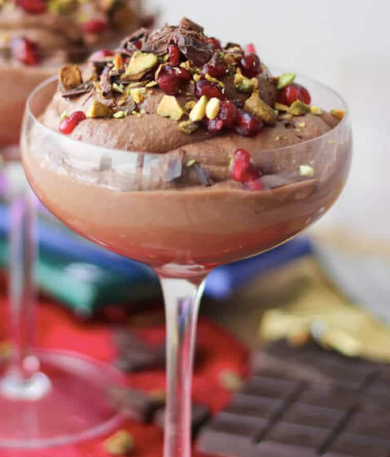 A wine glass filled with chocolate tahini mousse with pomegranate and pistachio. 