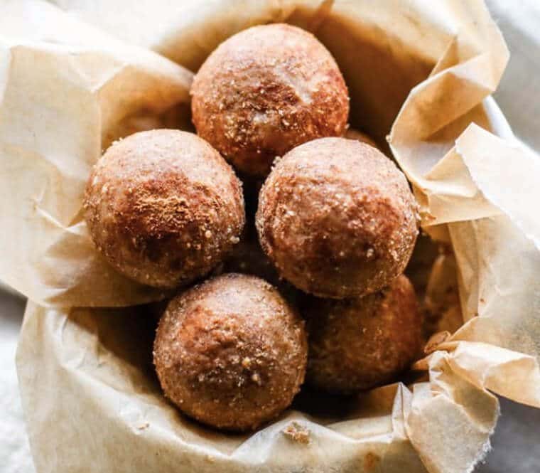 A bowl lined with parchment with cinnamon vanilla breakfast protein bites.