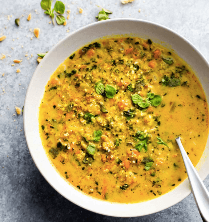 A bowl of curried cauliflower rice and kale soup.