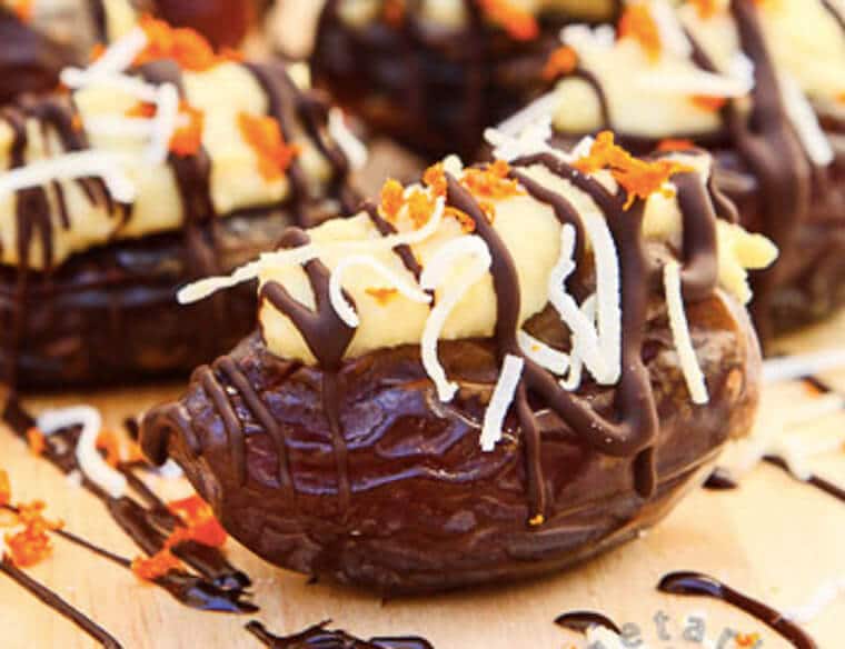 Close up photo of dark chocolate covered dates stuffed with orange coconut cream.