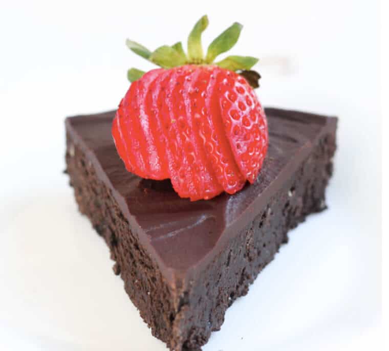 A piece of flourless chocolate cake with strawberry slices on top.