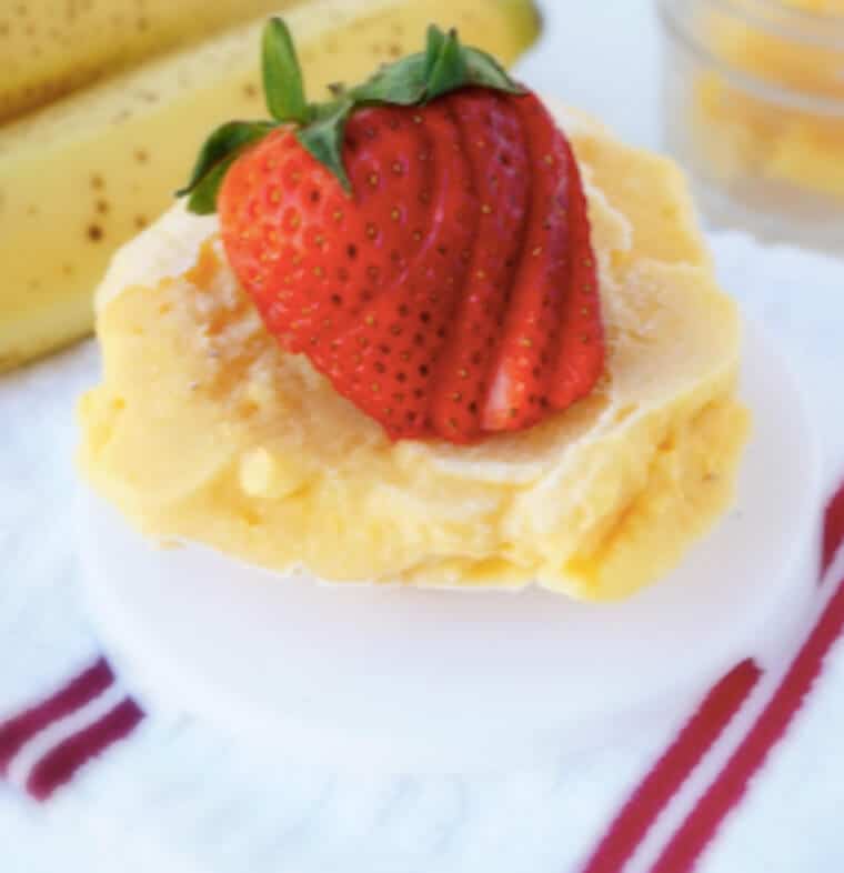 Close up of a mango banana sorbet with sliced strawberries on top.