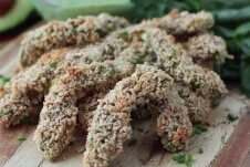 A stack of baked avocado fries with dip in the background.