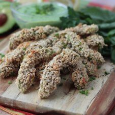A stack of baked avocado fries with dip in the background.