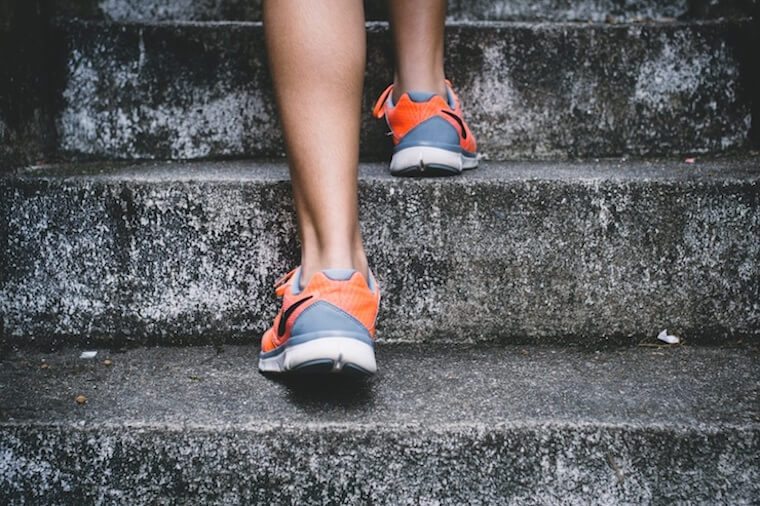 Image of a person wearing running shoes walking up stairs