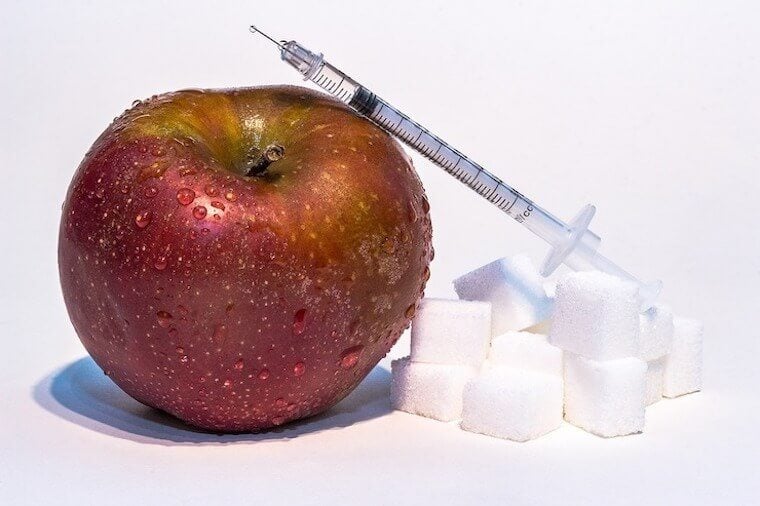 Image of an apple next to a needle and sugar cubes.