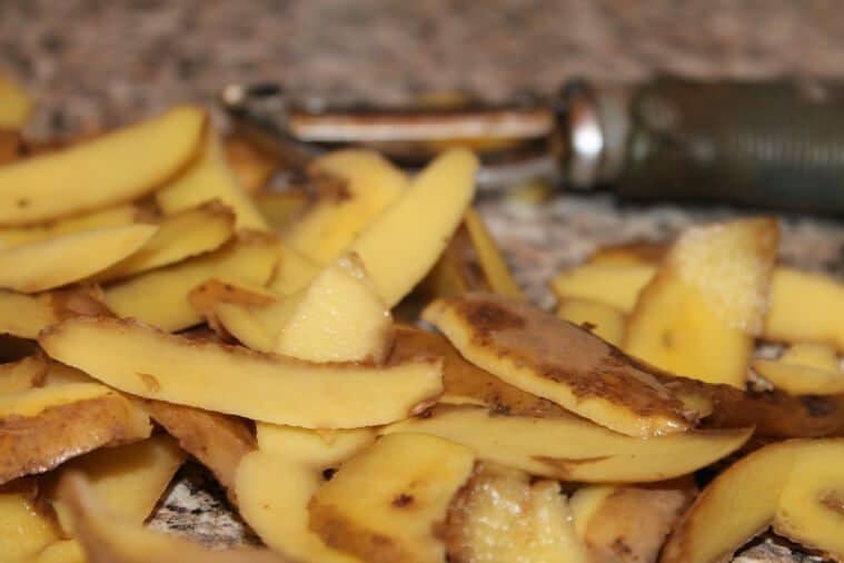 Potato peels with a peeler in the background