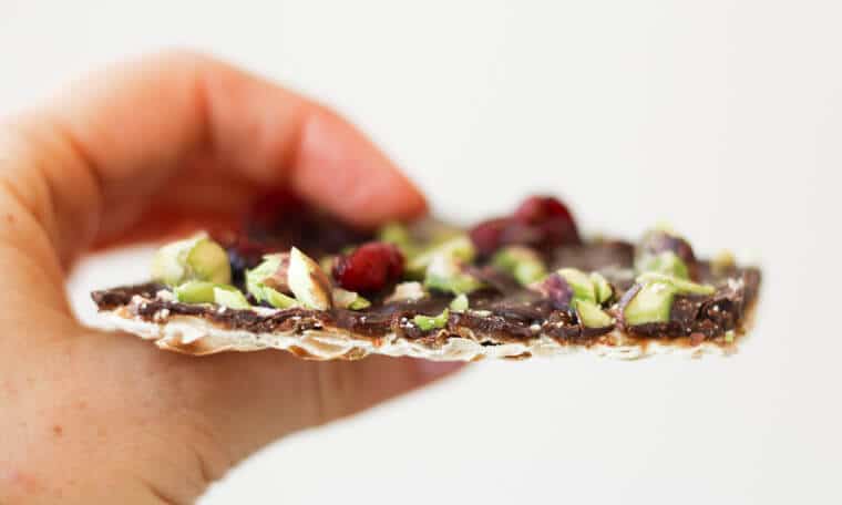 A close up of a person holding a piece passover matzo.