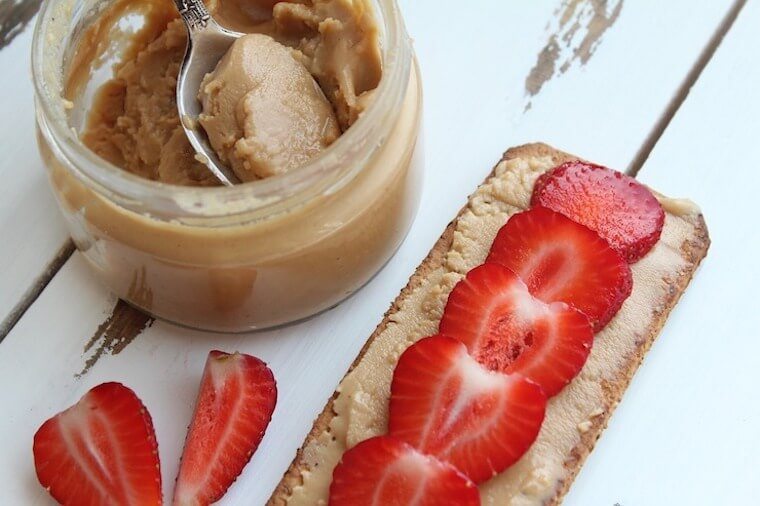 Birds eye view of nut butter and strawberries on toast next to a jar of strawberries.