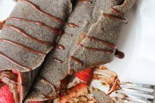 A chocolate buckwheat crepe being cut with a knife and fork.