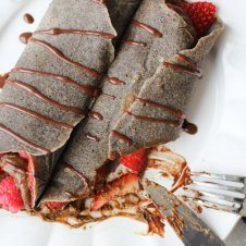 A chocolate buckwheat crepe being cut with a knife and fork.