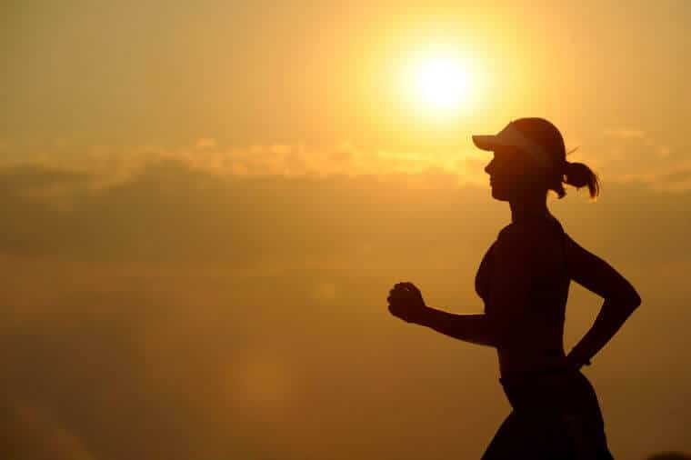 A woman running in front of a sunset.