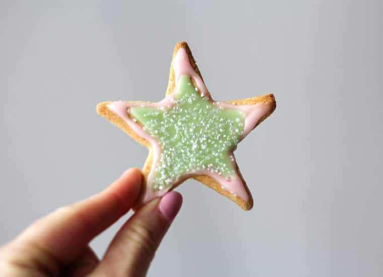 A hand holding a star shaped almond sugar cookies.