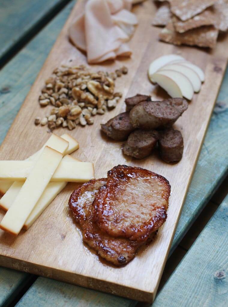 A serving platter with charcuterie on it, such as cheese, meats, and nuts.
