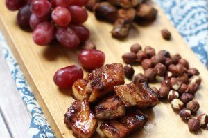 A serving platter with charcuterie on it, such as grapes, meats, and nuts.