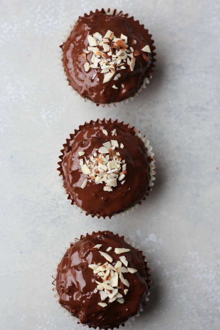 An overhead photo of a chocolate muffin with chocolate glaze with crushed almonds on top.