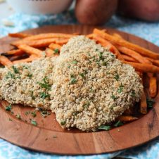 A brown plate with two gluten free fish and sweet potato chips.