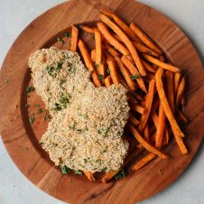 An overhead photo of a brown plate with two gluten free fish and sweet potato chips.