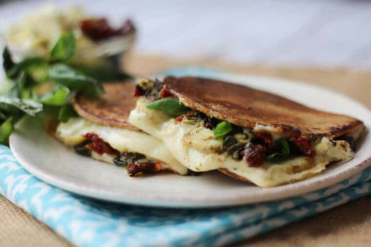 close up of artichoke and pesto grilled cheese on a white plate