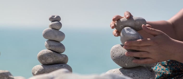 A hand stacking rocks.