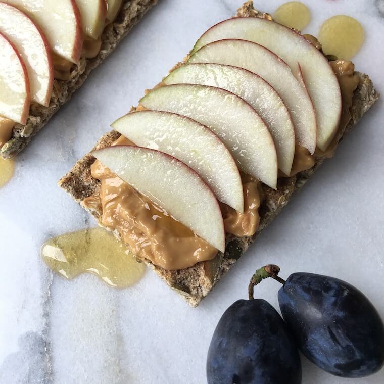 Overhead photo of a cracker with nut butter and sliced apple.