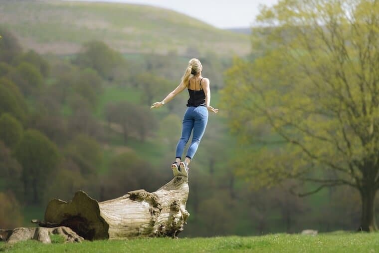 A person standing on a tree trunk. 