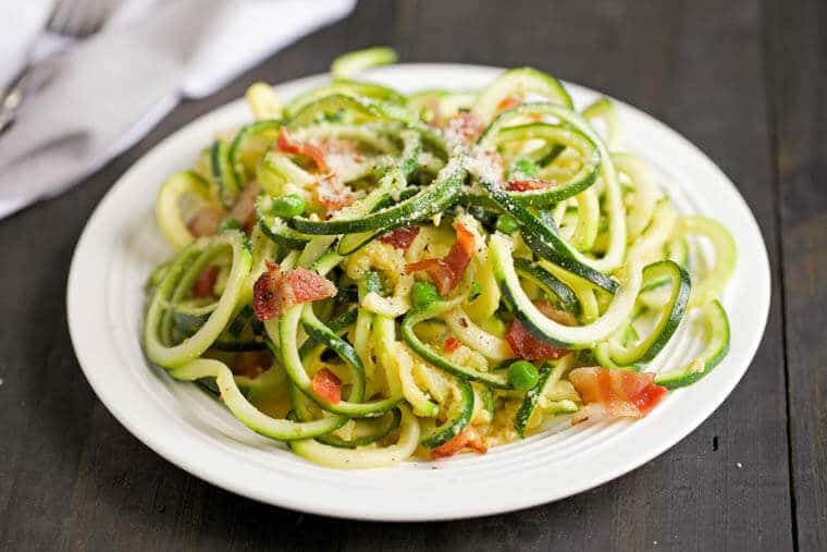 A white plate with zucchini carbonara.