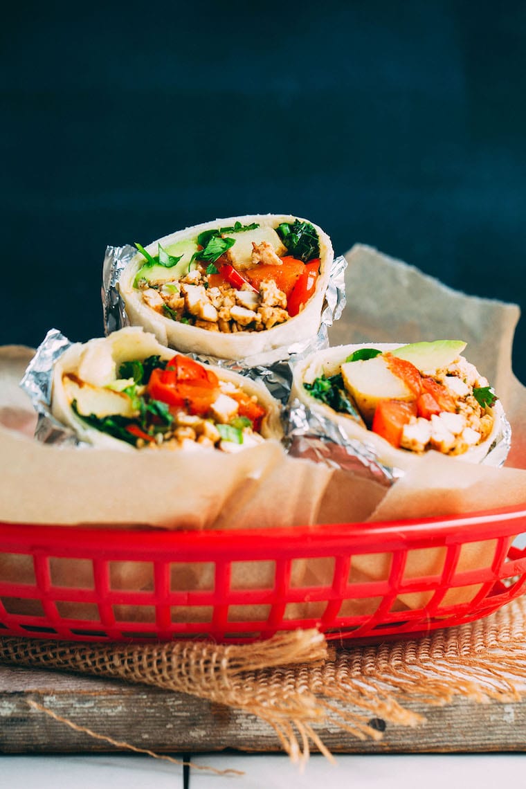 Three burrito halves sitting in a red plastic dish. 