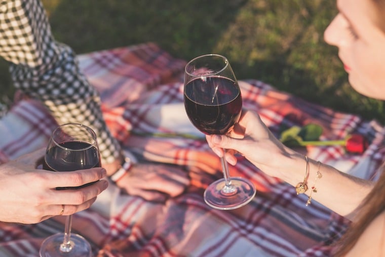 A person holding a wine glass with red wine.